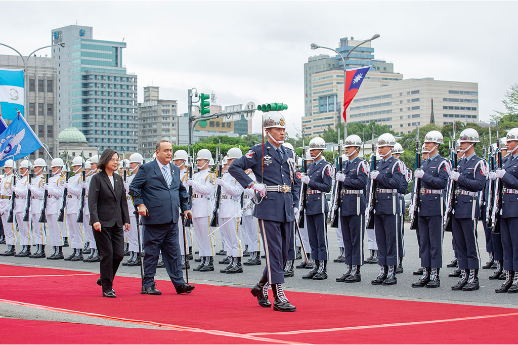 The President escorts a visiting leader of state past a tri-service honor guard.