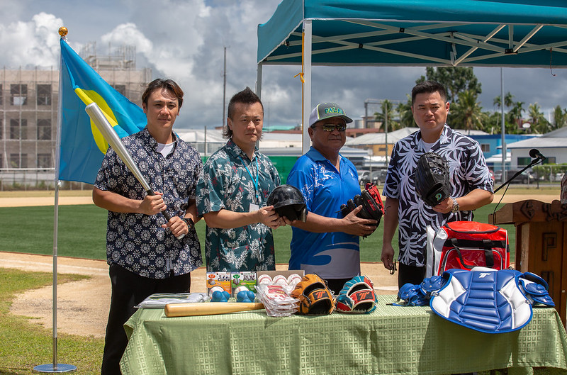 Managing Director Huang, and professional baseball players Hu and Chen hand over baseball supplies to President of the Palau Major League Mlib Tmetuchl.