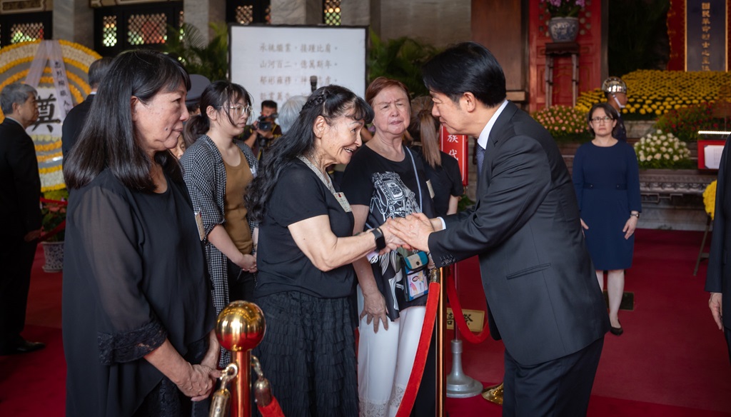 The President shakes hands and pays respect to the representatives of the survivors.
